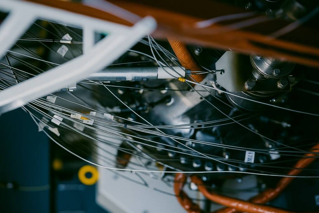 Zbliżenie na zaawansowany reaktor przemysłowy z siecią przewodów i metalowych elementów w zamkniętej instalacji technologicznej.